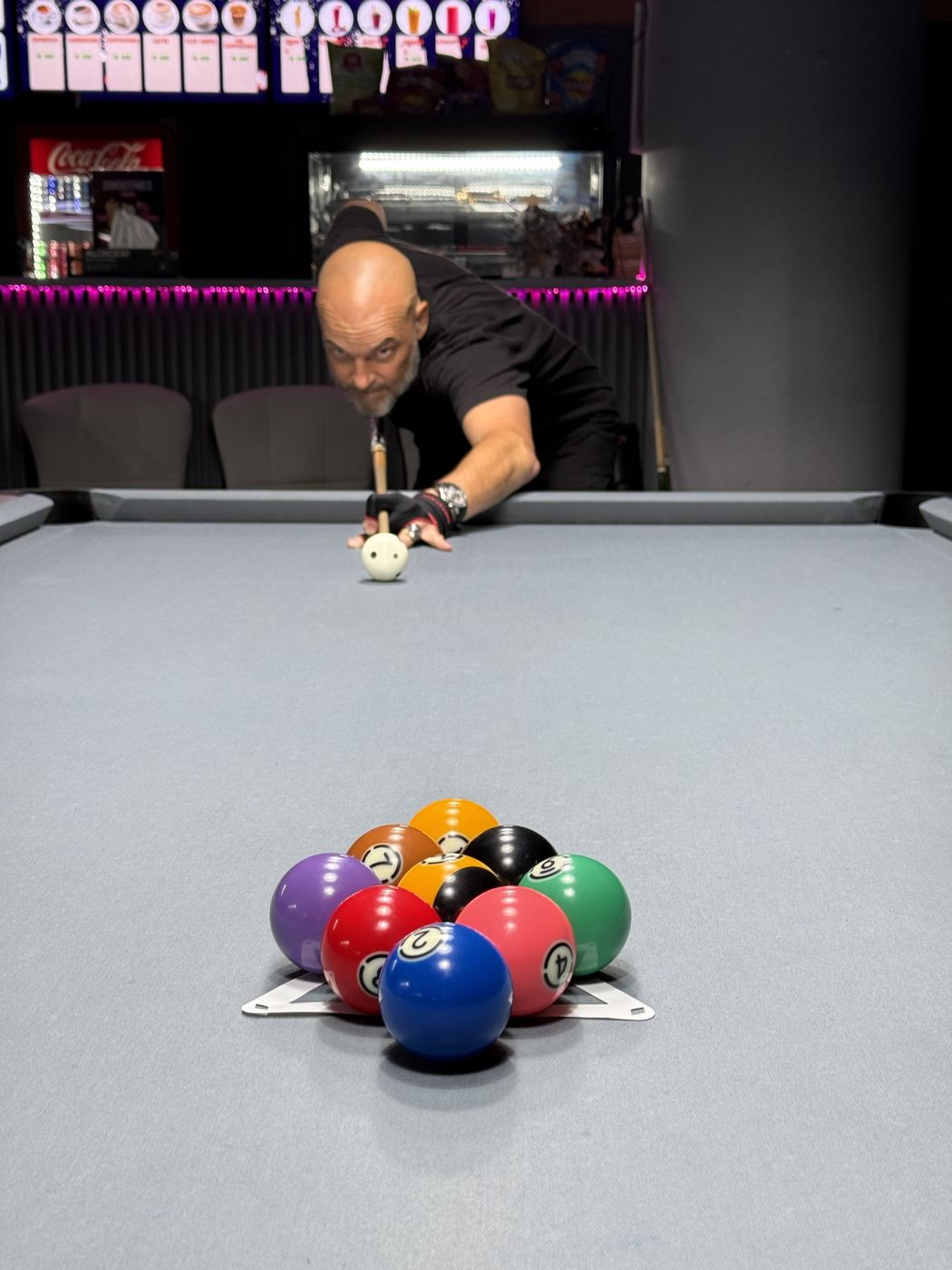 Racked balls on a grey pool table at RACK N ROLL