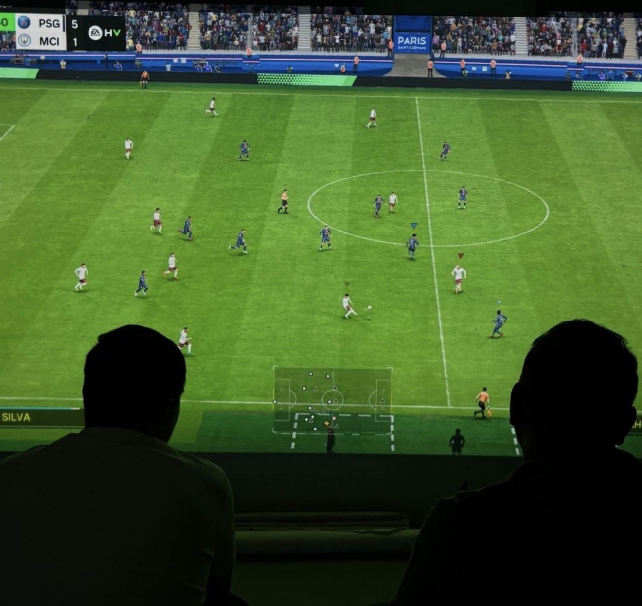 Two players on PlayStation 5 football on a big screen